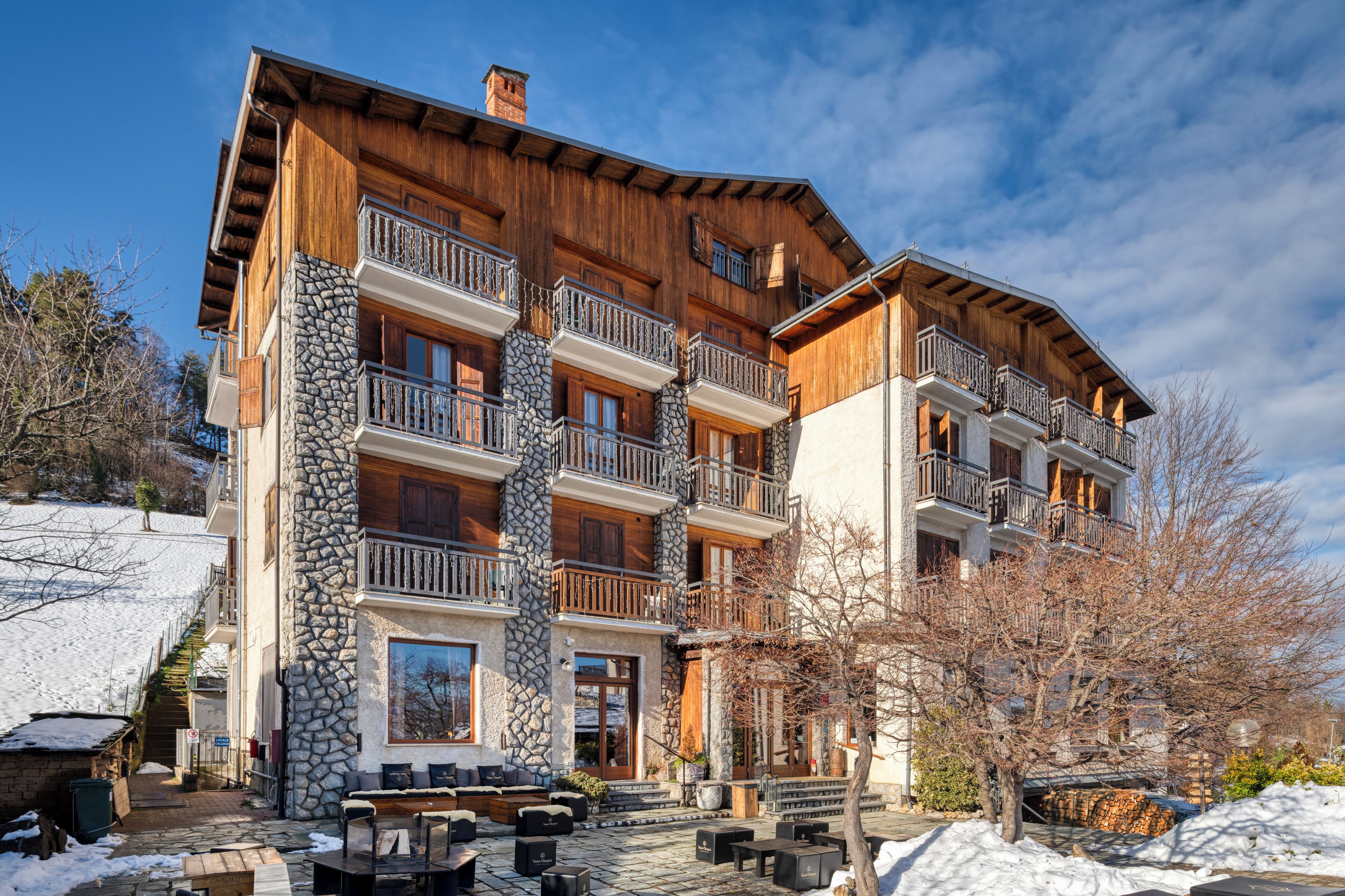 A multi-story wooden building with stone accents, balconies, and outdoor seating.