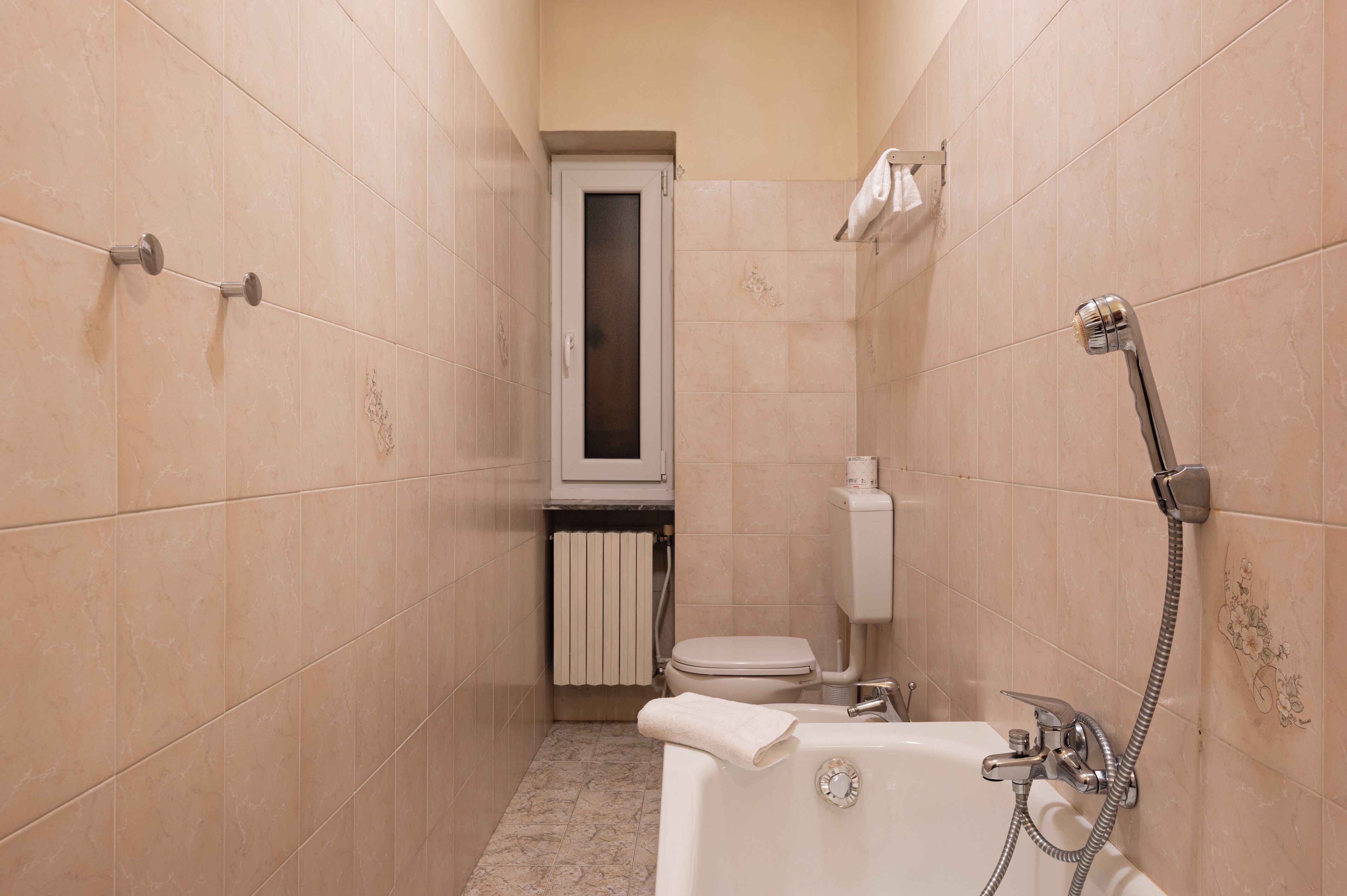 Een compacte badkamer met een bad, toilet en douche.