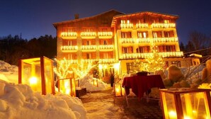 A hotel with multiple balconies, a snow-covered pathway, and outdoor lighting.
