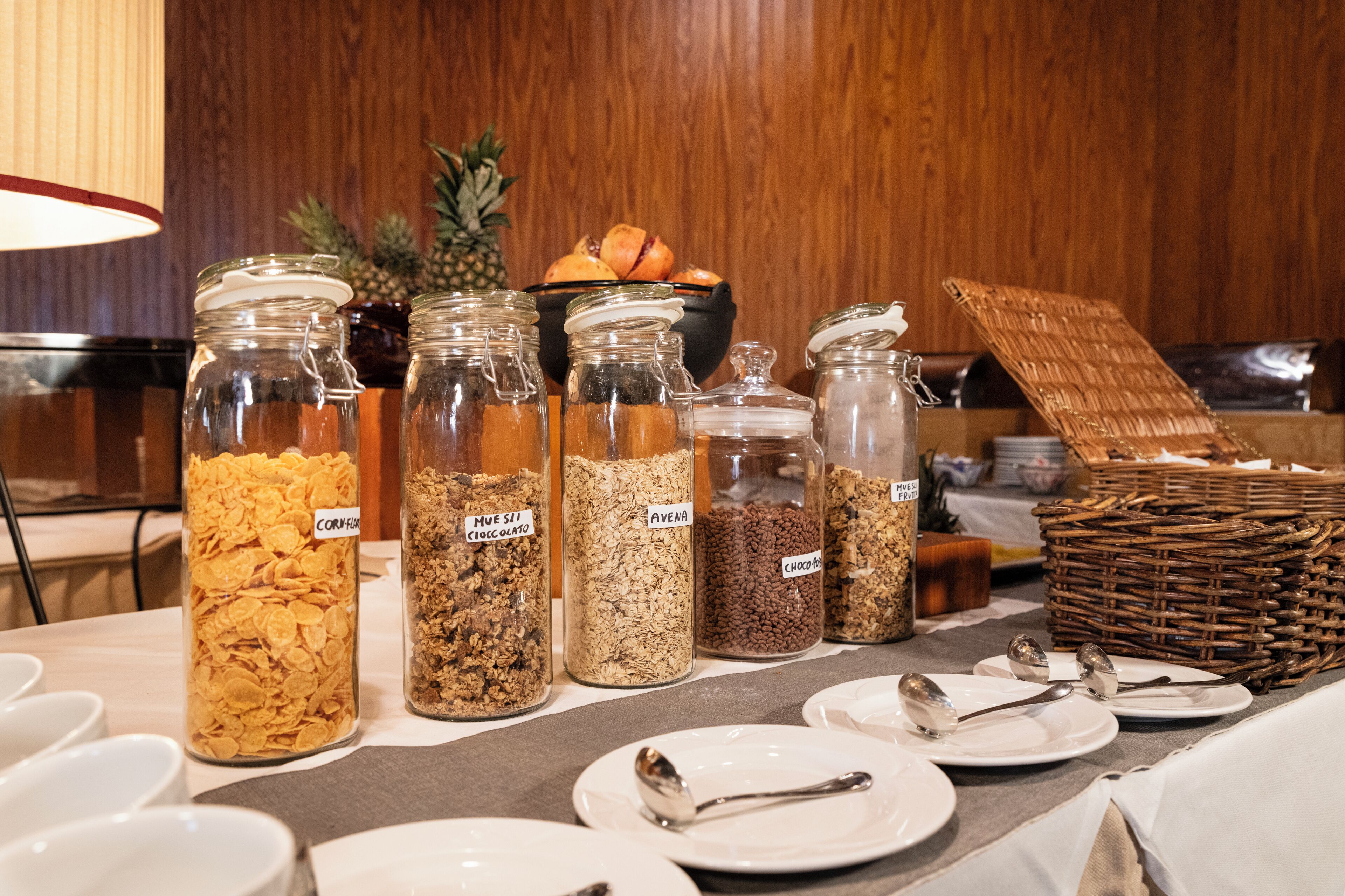 A buffet table with various food items in glass jars labeled with names like 'CORN-FIRE' and 'AVENA'.
