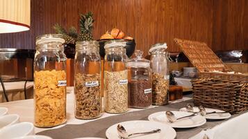 A buffet table with various food items in glass jars labeled with names like 'CORN-FIRE' and 'AVENA'.