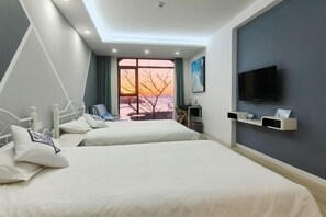 A hotel room with two beds, a TV, and a large window with a sunset view.