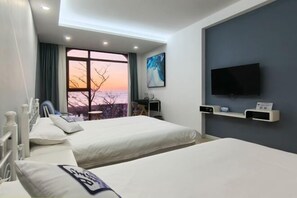A hotel room with two beds, a large window with a view, a flat-screen TV, and a desk with a chair. - Xihai Hostel (Shengsi)