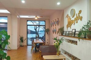 A dining area with a view of the outdoors, a ceiling fan, and wall-mounted decorations. - Xihai Hostel (Shengsi)