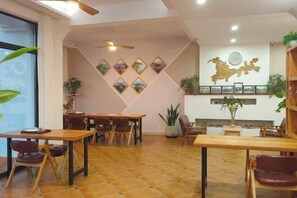 A hotel lobby with a dining area, wooden tables, and chairs. - Xihai Hostel (Shengsi)