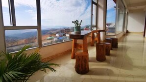 A spacious room with large windows offering a view of a mountainous landscape.