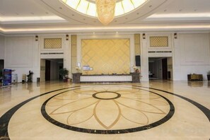 A spacious lobby with a central reception desk, a large chandelier, and a decorative floor pattern. - Dongjiang Holiday Hotel (Danyang)
