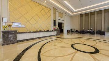 Un hall de hotel con una recepción, un gran muro estampado y un diseño de piso circular.