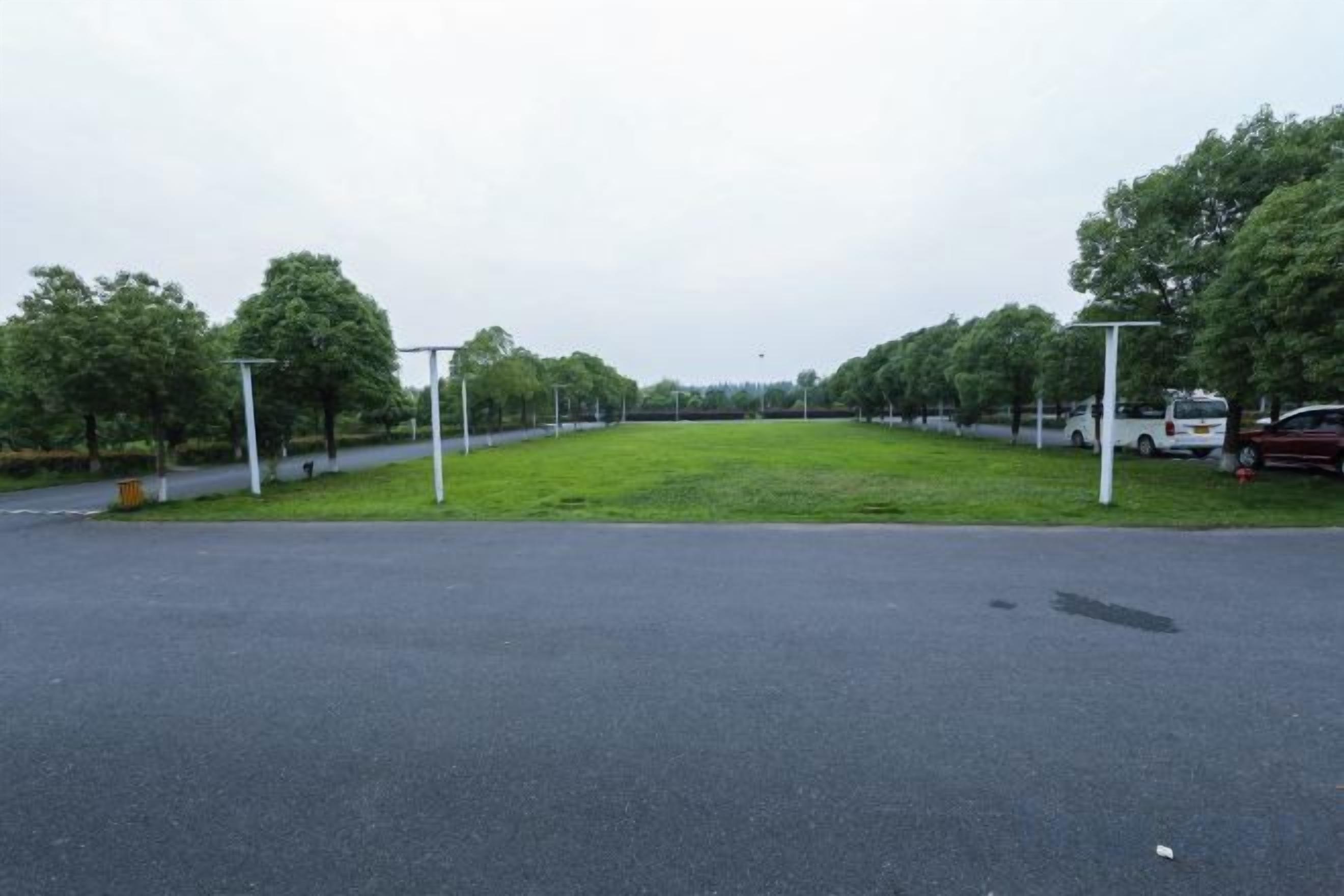 A parking lot with a grassy area and trees.