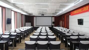 A conference room with rows of tables and chairs, a projector screen, and a whiteboard.