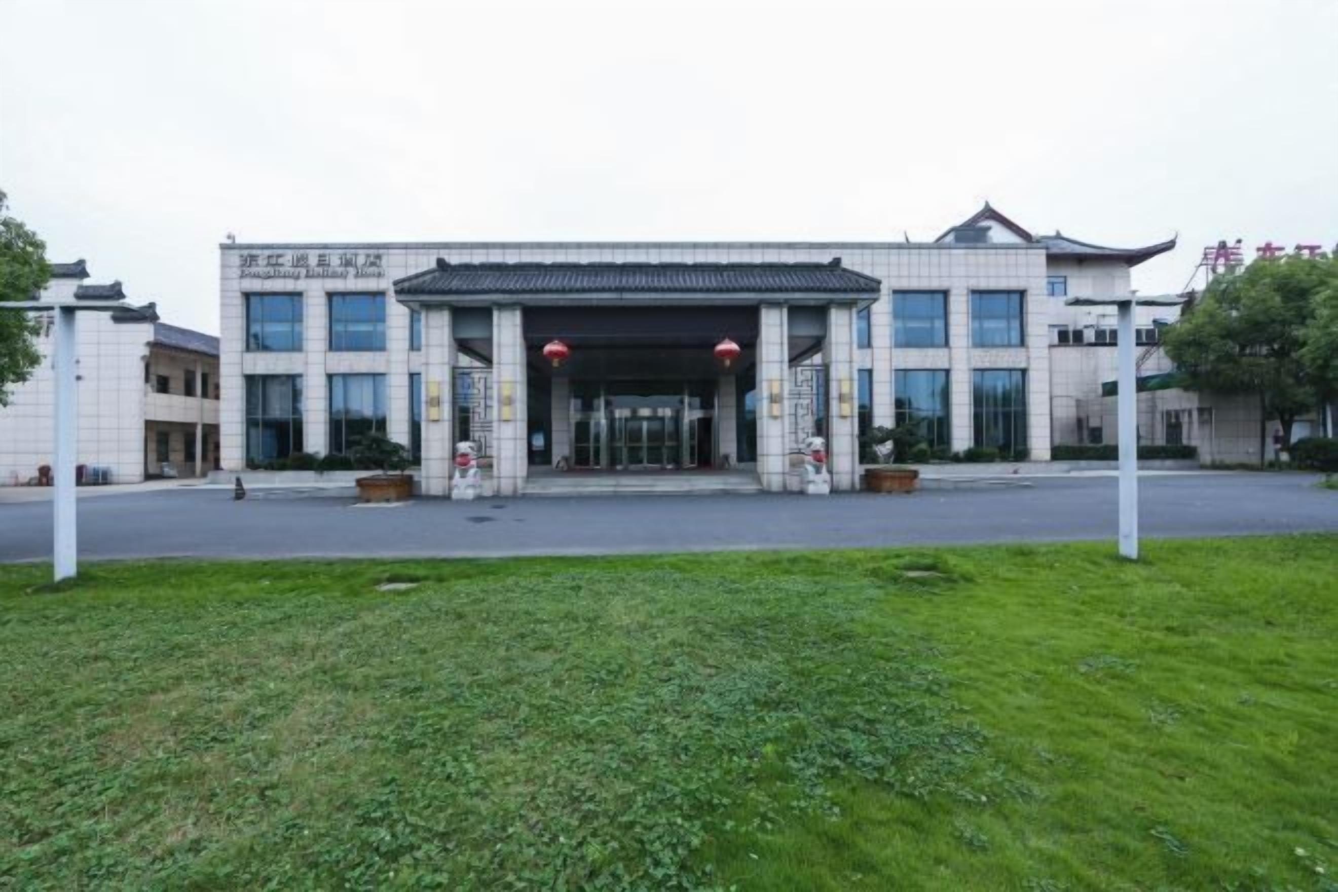 A modern building with a traditional architectural style, featuring a large entrance with a covered walkway, surrounded by a well-maintained lawn.