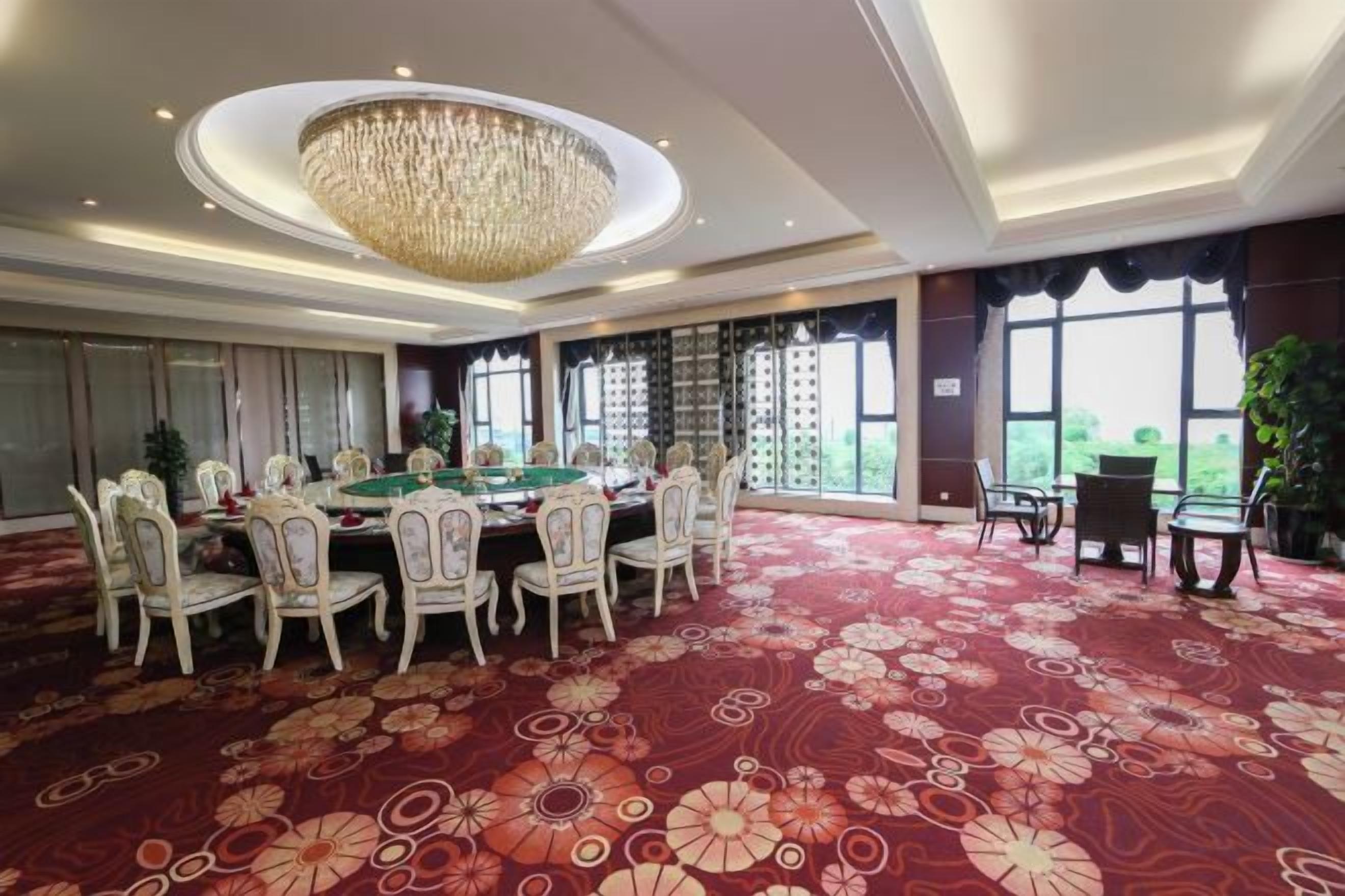 A spacious room with a pool table, multiple chairs, a chandelier, and large windows.