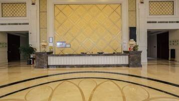 A reception area with a reception desk, a large decorative wall, and a polished floor.