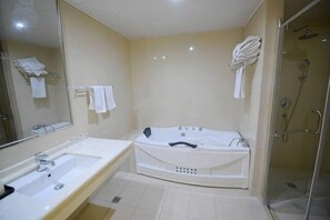 A bathroom with a bathtub, a sink, a mirror, and a shower area.