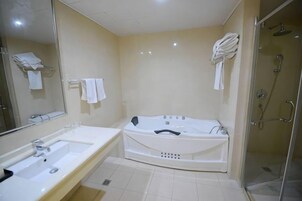 Un baño con bañera, lavabo, espejo y zona de ducha.