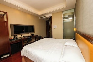 Une chambre d’hôtel comprenant un lit, un bureau avec une chaise, une télévision et un miroir.