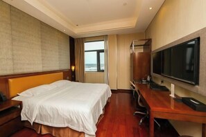 Une chambre d’hôtel avec un lit, un bureau, une télévision et une fenêtre donnant sur un paysage agréable.