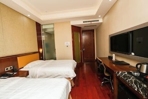 Une chambre d’hôtel avec deux lits, un bureau doté d’un téléviseur à écran plat, une machine à café et un minibar.