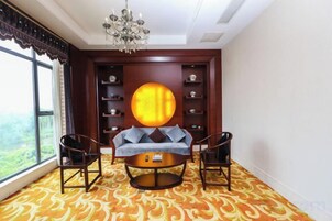 Una habitación con una mesa redonda, dos sillas, un sofá, una araña y una estantería.