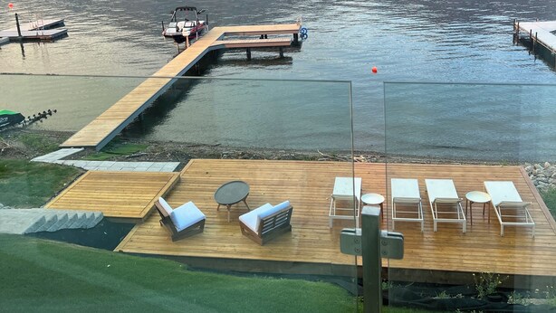 A lakeside deck with lounge chairs and a wooden dock extending into the water.