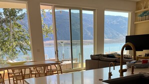 A modern kitchen with large windows overlooking a lake and mountains.