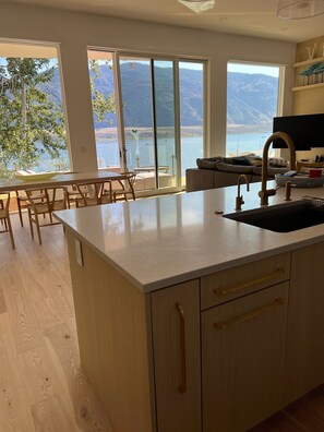 Cozinha moderna com grandes janelas dando vista para um lago e montanhas.