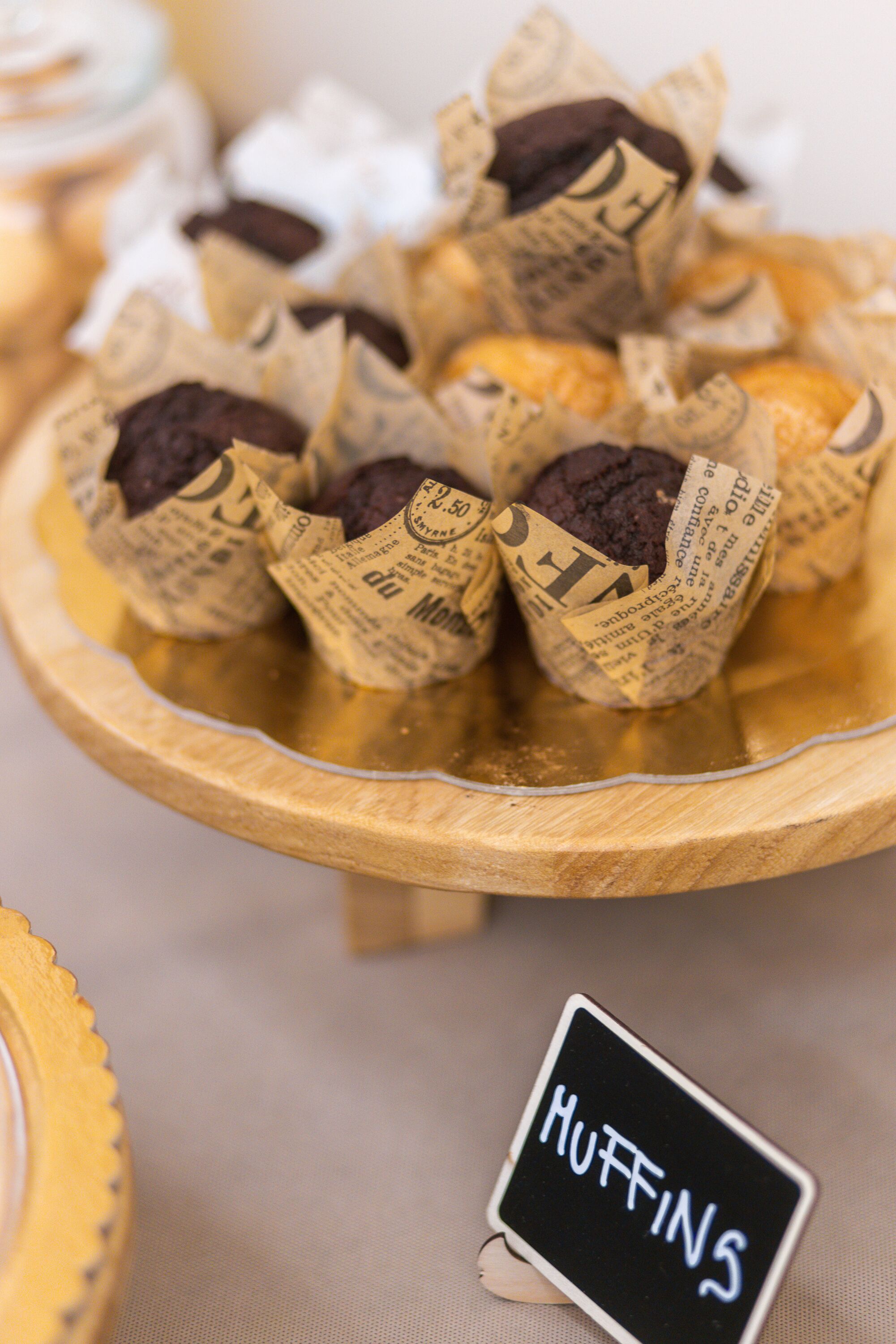 A tray of muffins wrapped in newspaper-style packaging with a sign labeled "HUFFINS".