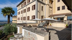 Un immeuble à plusieurs étages doté d’une terrasse sur le toit, aménagée avec des espaces de détente en plein air et des parasols.