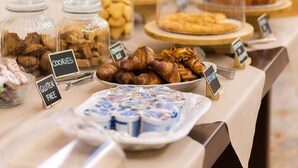 Une table de buffet proposant divers aliments, notamment des biscuits, des pâtisseries et des produits laitiers, avec des étiquettes indiquant les options sans gluten.