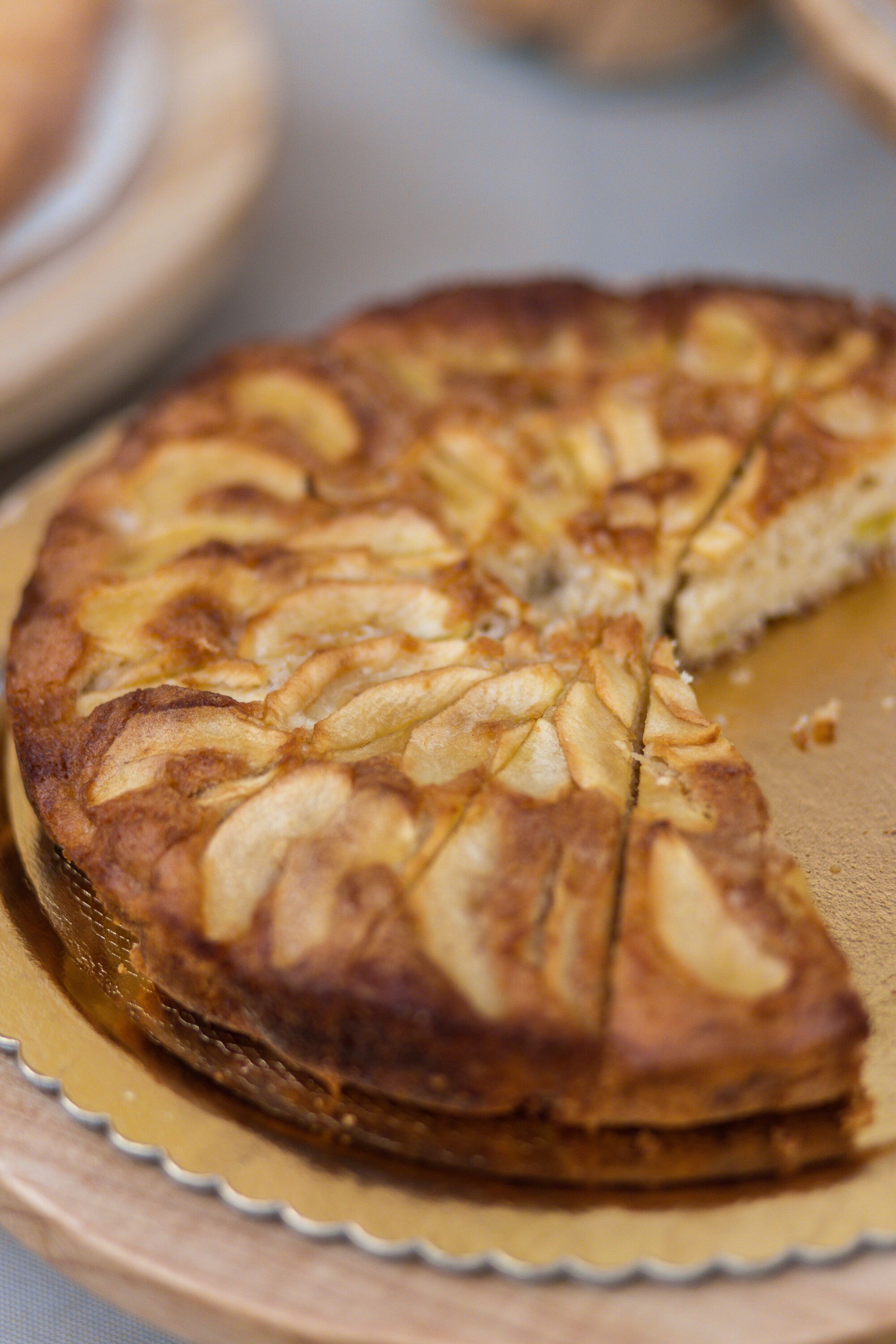 A round cake with a golden-brown crust and sliced pieces on a golden plate.
