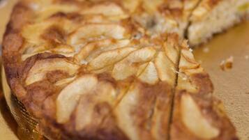 A round cake with a golden-brown crust and sliced pieces on a golden plate.