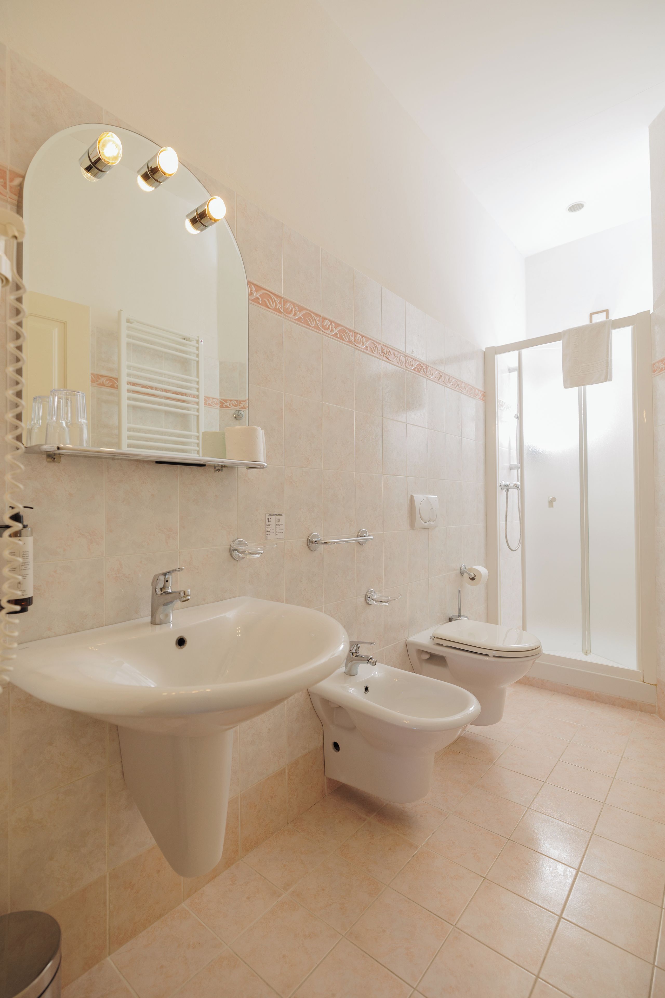 A bathroom with a large sink, a bidet, a toilet, and a shower.