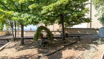 Pátio com pérgola, bancos e parede de pedra.