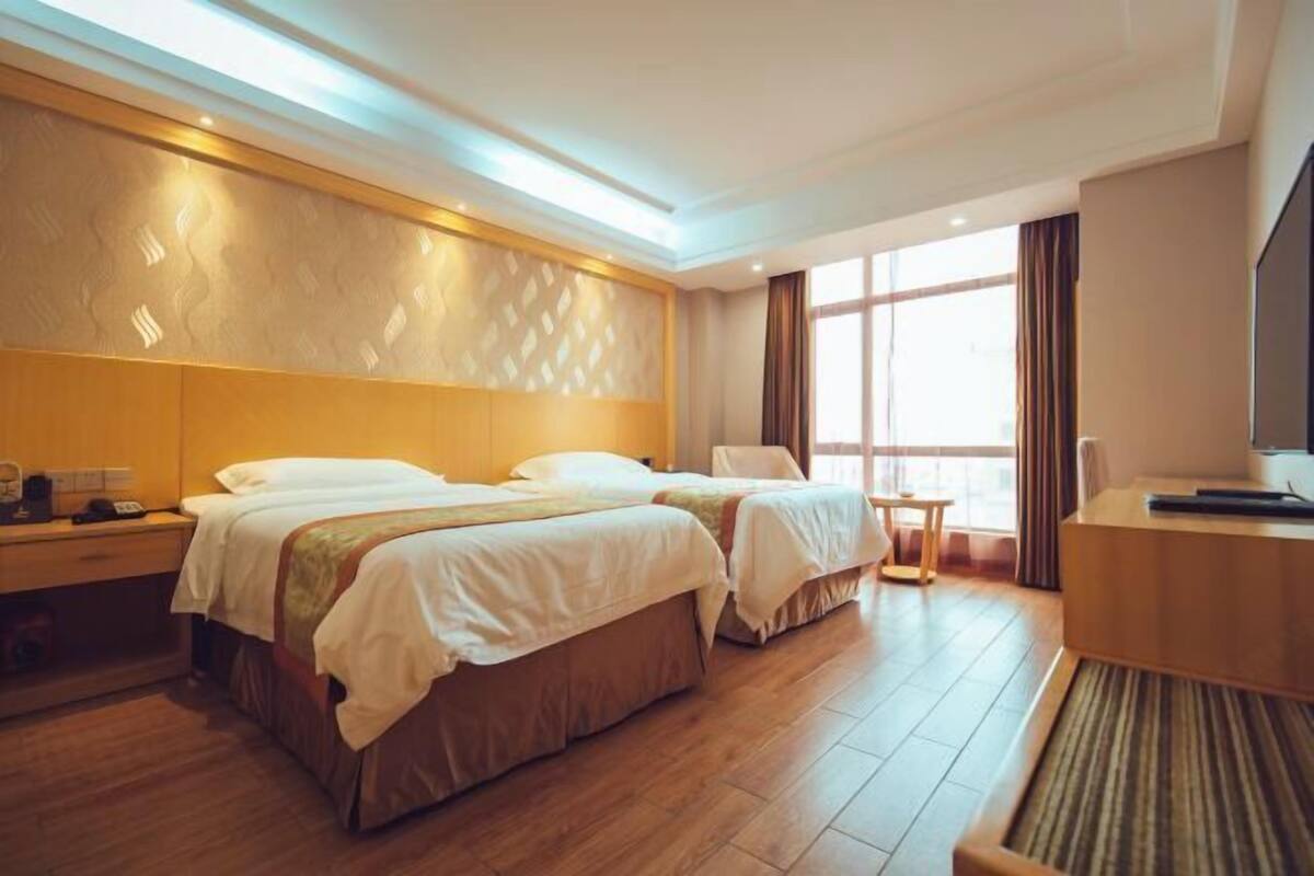Habitación de hotel con dos camas, un escritorio, una silla y un televisor.