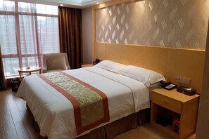 A hotel room with a large bed, a bedside table, a chair, and a small table. - Jing Hao Hotel (Shanwei)