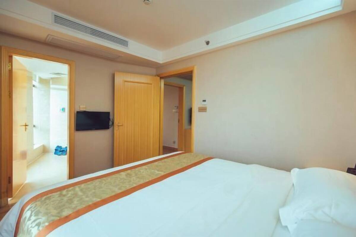 A hotel room with a bed, a television, and wooden doors.