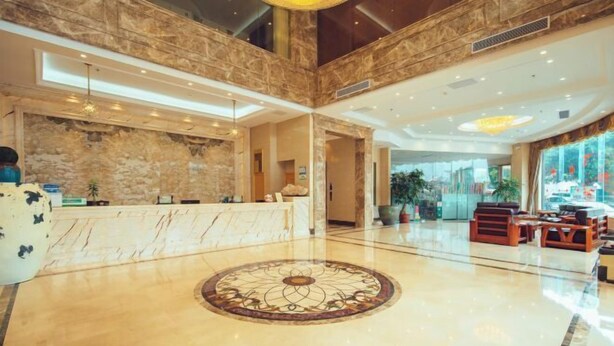Un vestíbulo amplio con una recepción de mármol, un diseño decorativo en el suelo y zonas de estar.