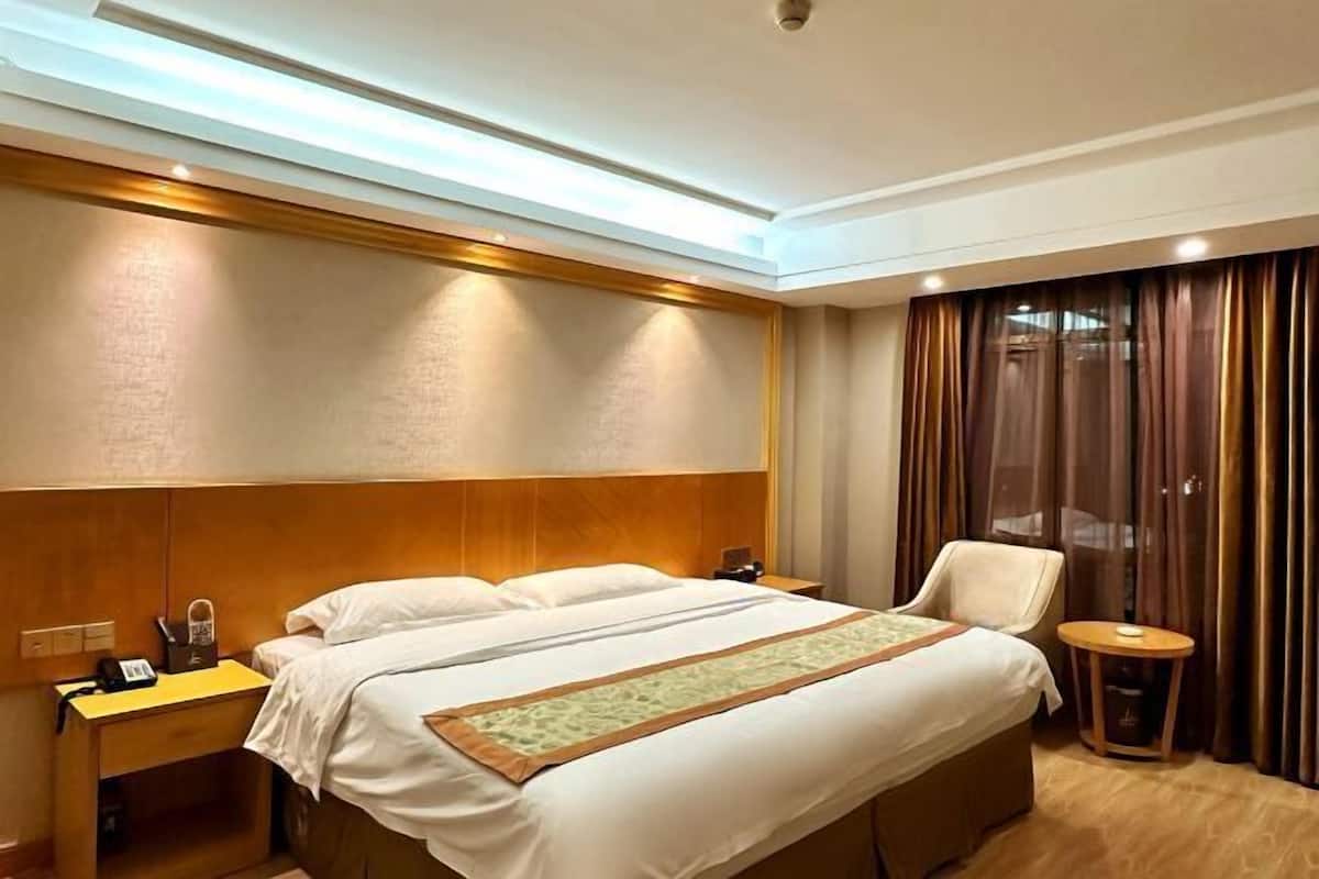 Una habitación de hotel con una cama, una silla, una mesita y un escritorio con teléfono.