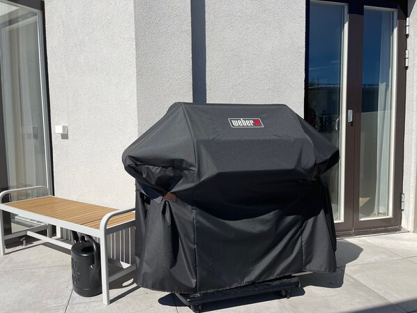 Una parrilla Weber con una mesa y sillas dispuestas afuera de un edificio.