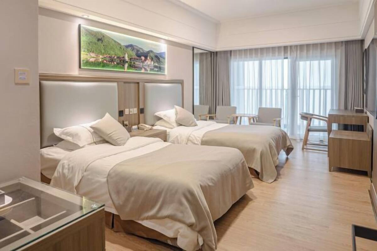 A hotel room with two beds, a desk, and a chair.
