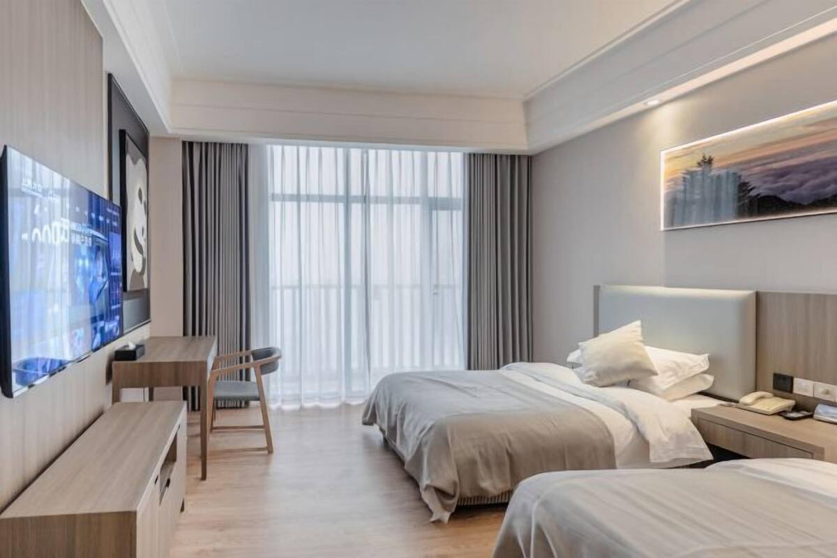 A modern hotel room with a large bed, a desk, and a TV.