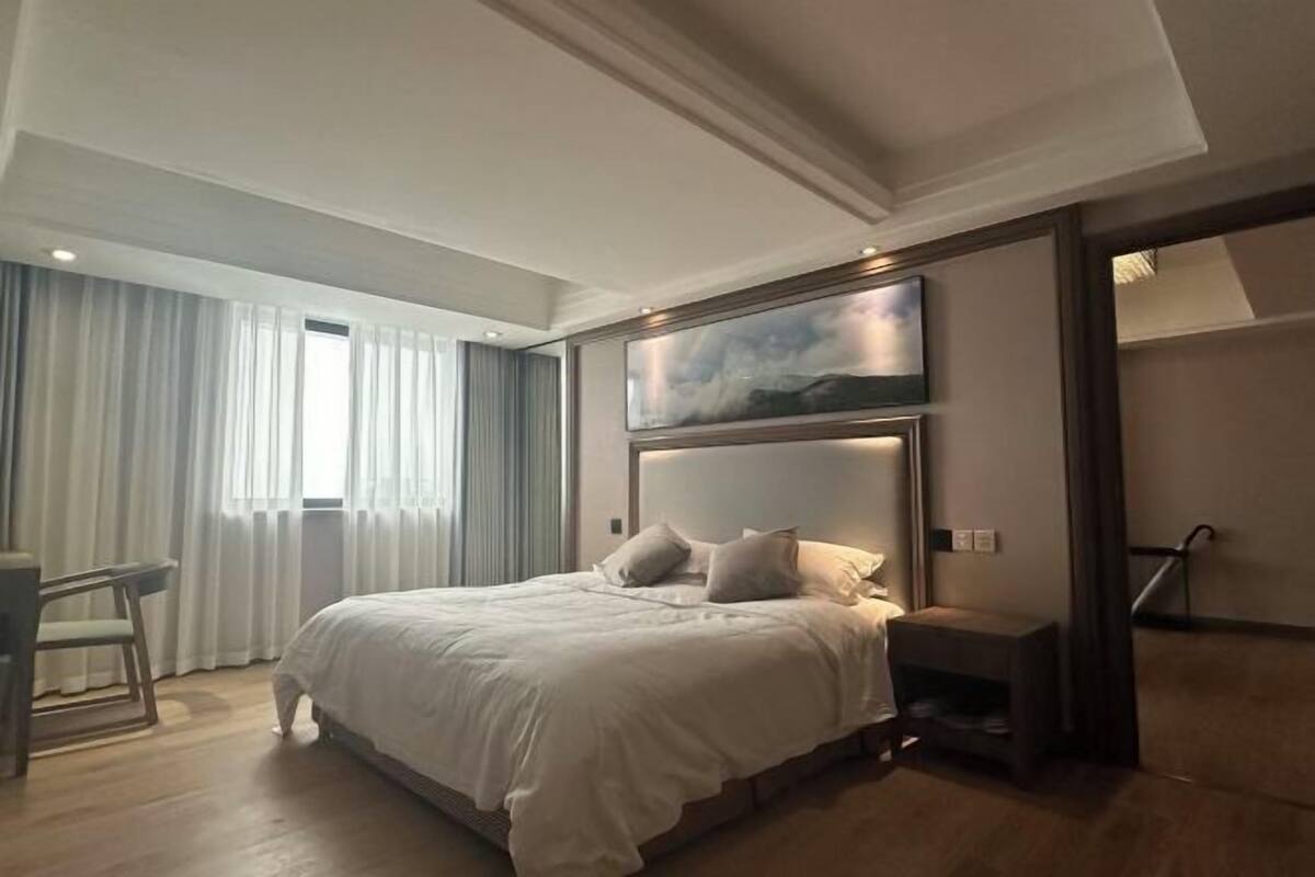 A hotel room with a large bed, a desk, and a chair.