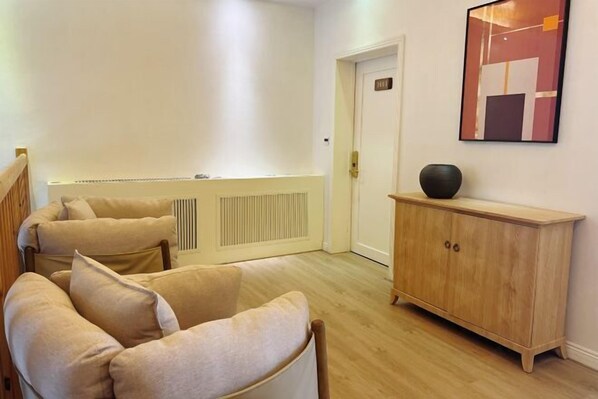 A room with a beige sofa set, a wooden cabinet, and a framed abstract painting on the wall. - Yingxue Hotel (Dayi)