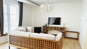 Un salon moderne avec un canapé en bois, une cheminée, un téléviseur et un lustre.