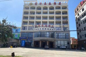 A multi-story building with a central entrance, large windows, and signage indicating it is a hotel. - Ledong Fuhua Haoting Hotel (Huangliu Branch) (Ledong)