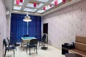 A dining area with a table and chairs, a blue curtain, and a patterned wall. - Ledong Fuhua Haoting Hotel (Huangliu Branch) (Ledong)