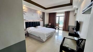 A modern hotel room with a large bed, a desk, a chair, and a television.