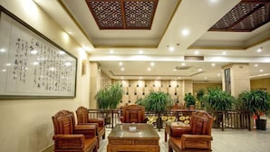 A traditional-style lobby with wooden furniture, a large calligraphy piece on the wall, and potted plants. - Ledong Fuhua Haoting Hotel (Huangliu Branch) (Ledong)