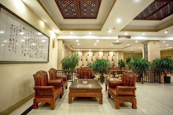 Un hall d’entrée de style traditionnel, avec des meubles en bois, une grande œuvre calligraphique accrochée au mur et des plantes en pot.