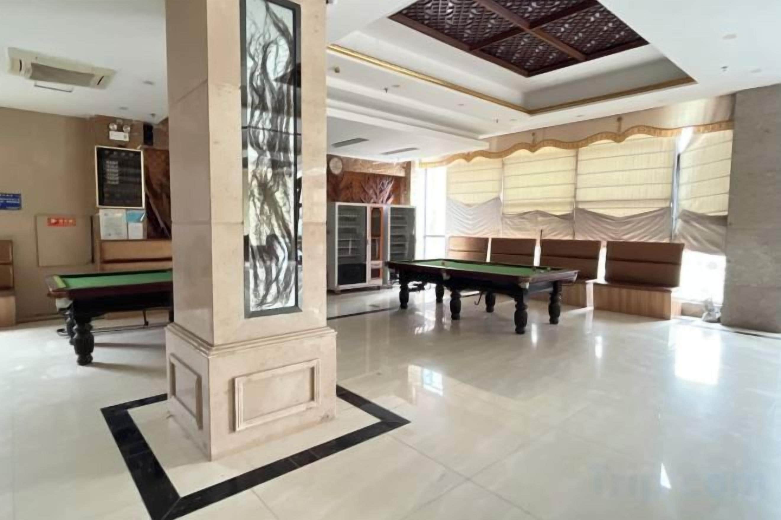 Un vaste espace intérieur comprenant une table de billard, une table de snooker et une grande colonne ornée d’un motif décoratif.